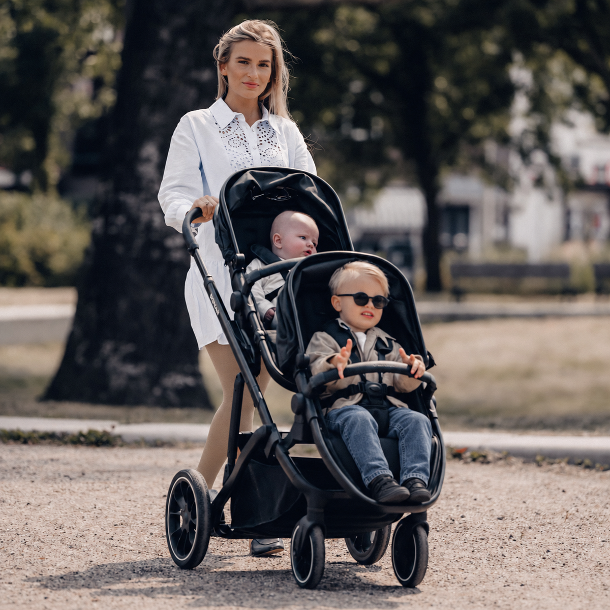 The DERYAN EVY V2 Duo Pram in black has two seats and a design that can be folded with one hand. The model has adjustable seats and a footrest, a sun canopy with SPF fifty plus, a suspension system and a five-point harness for both seating positions.